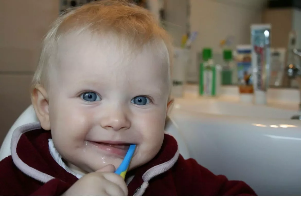 Uśmiechnięty chłopiec myje zęby mleczne