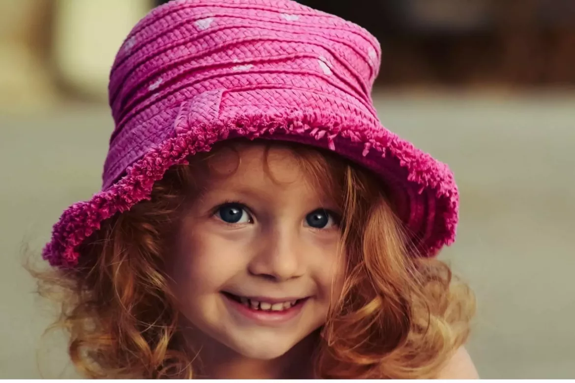 Uśmiechnięta dziewczynka w kapelusiku ma leczyć ubytki w zębach