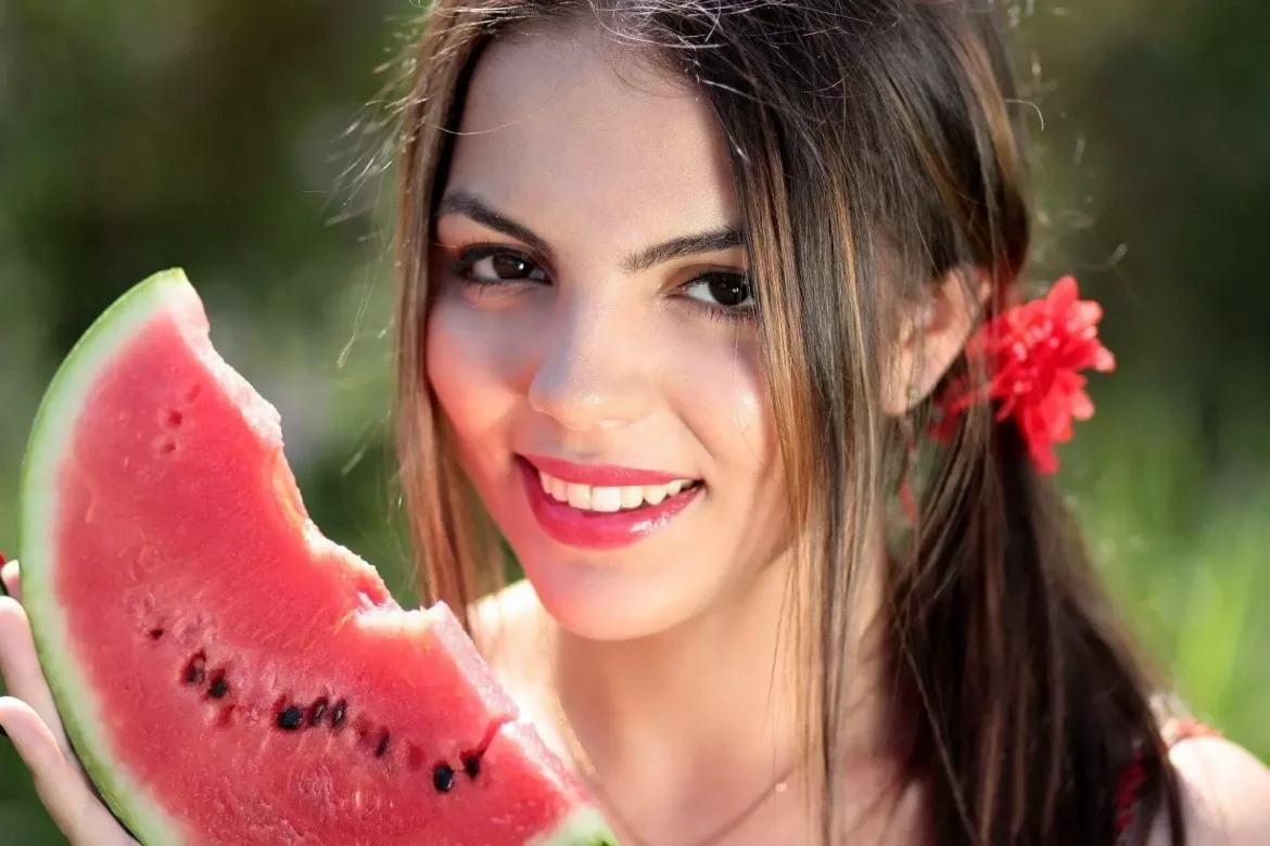Uśmiechnięta dziewczyna stosuje biała dietę trzyma plaster arbuzaa
