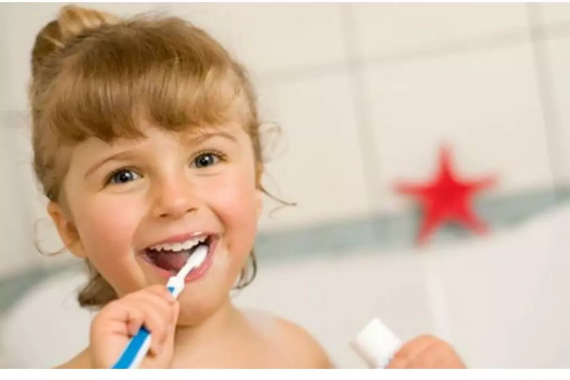 Uśmiechnięta dziewczynka myje zęby szczoteczką do zębów