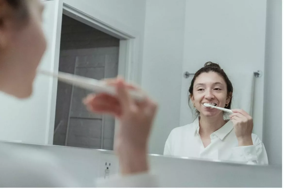 dziewczyna przed lustrem czyści swoje krzywe zęby