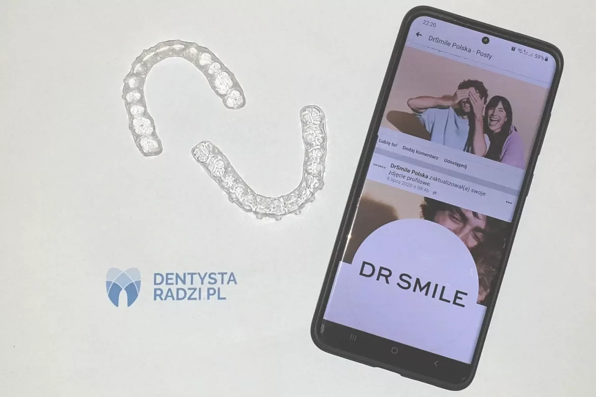 Komórka z ekranem z napisem Dr SMile. Obok dwie nakładki prostujące na zęby i logo dentysta radzi pl